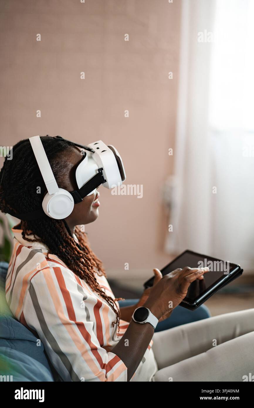 Young Black woman wearing VR headset using tablet Stock Photo