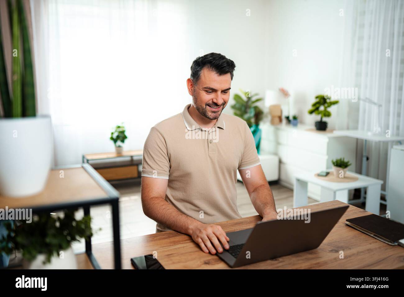 Smiling man working on laptop from home office Stock Photo