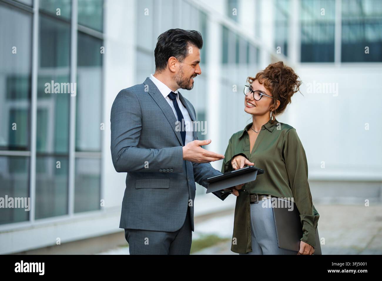 Business colleagues collaborating on a project, using a digital tablet outdoors Stock Photo