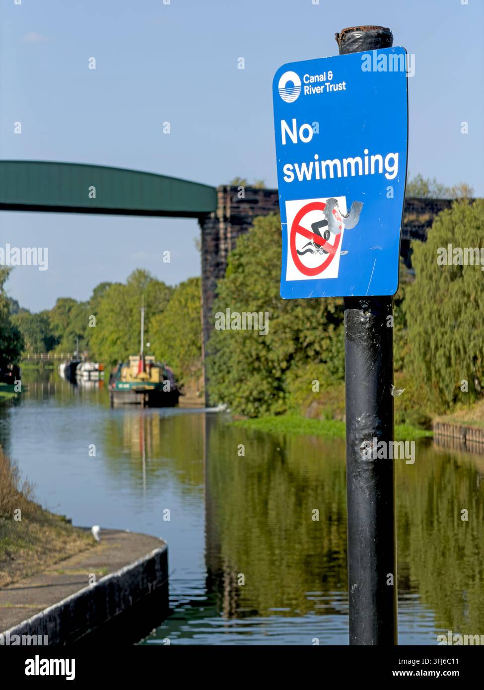 No swimming sign beside the River Weaver, warning against entering the water during warm weather when open-water swimming may be tempting. Stock Photo