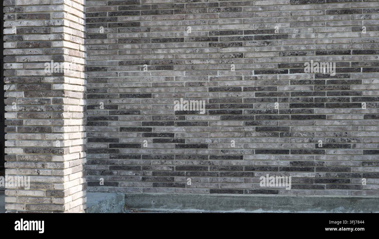 Facade cladding using long, linear clinker bricks. Decorative masonry featuring a mélange gradient of gray and anthracite tones. Stock Photo