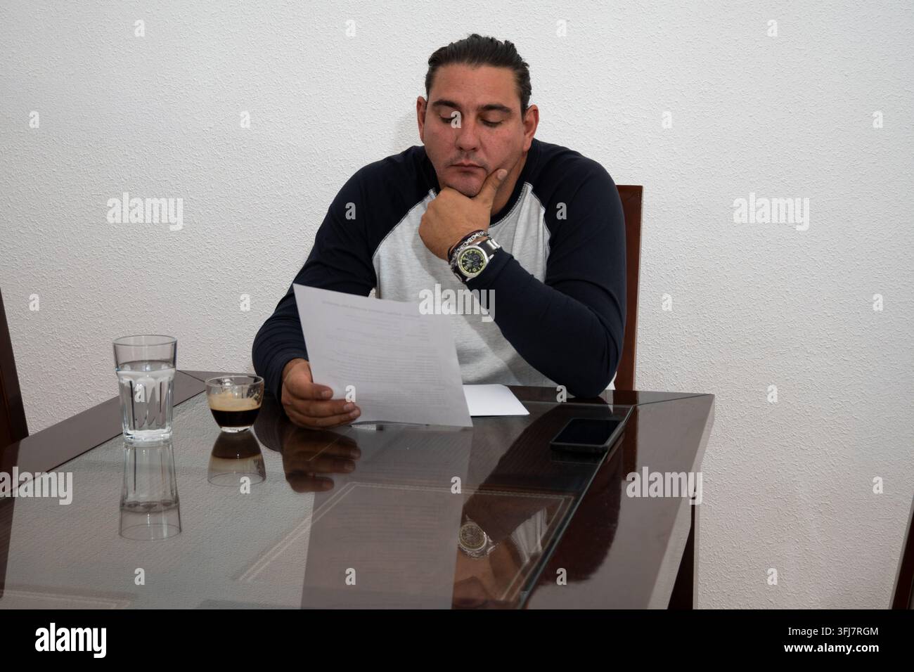 Man concentrating while reviewing important paperwork at a table with coffee Stock Photo
