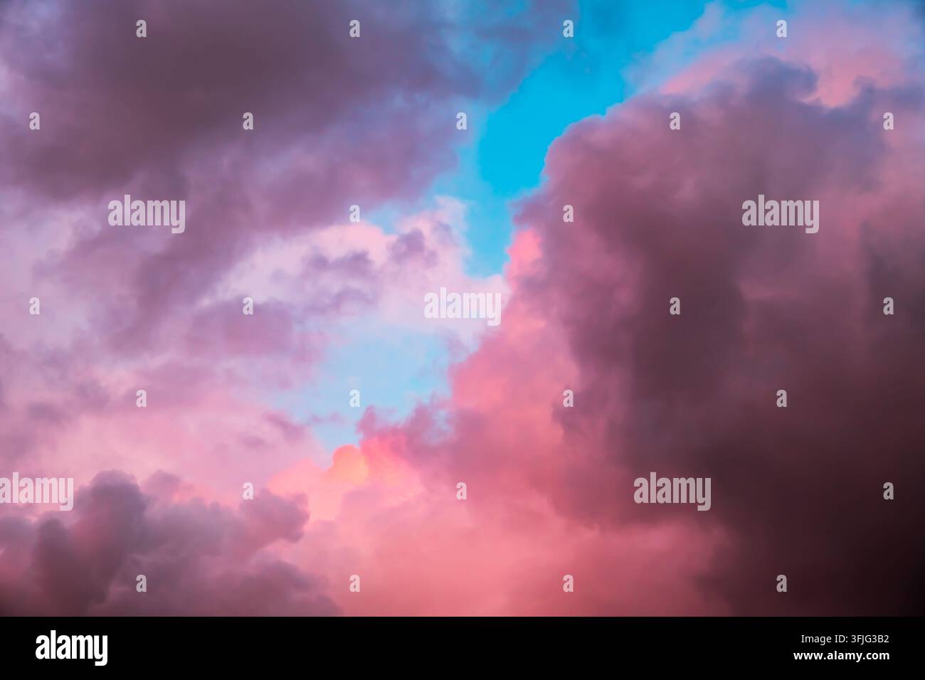Pink and purple cumulus clouds float in a blue evening sky. Sunset colors, dramatic atmosphere, natural background. High quality photo Stock Photo