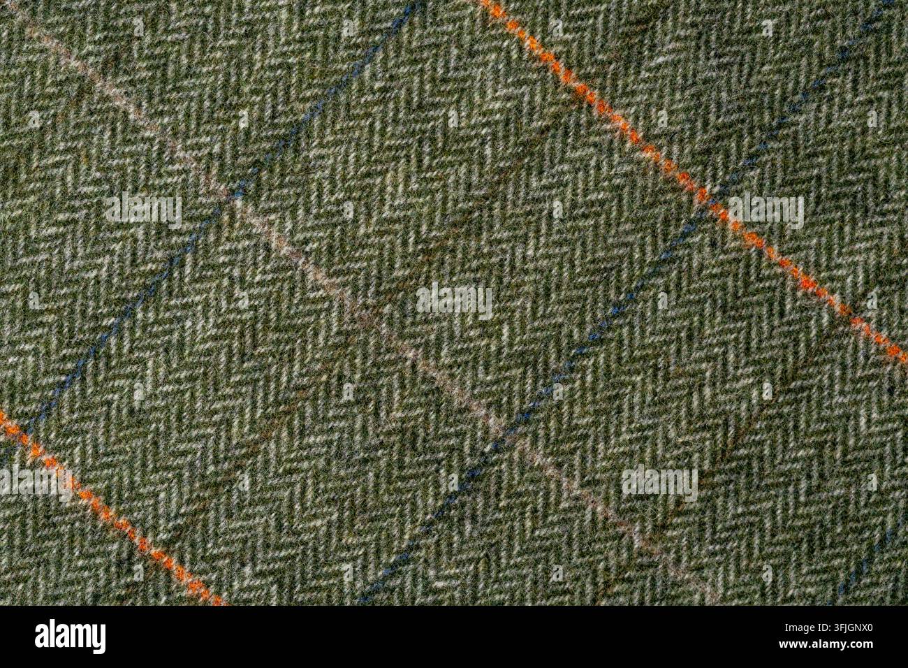 Macro view of coarse green woven fabric with visible gray fibers and irregular orange and blue threads. The detailed textile surface creates a natural Stock Photo