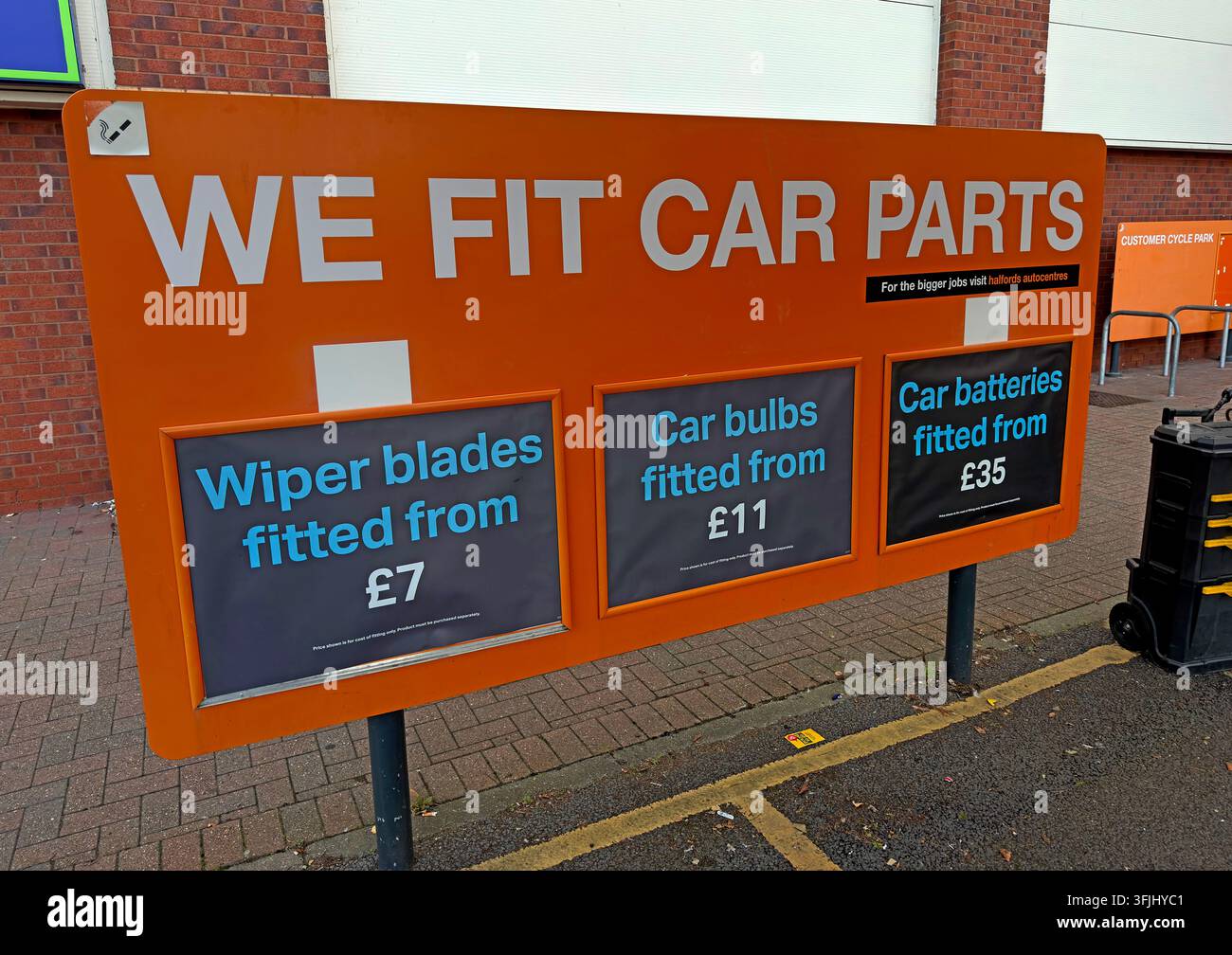 Halfords We Fit Car Parts sign advertising fitting of wiper blades, car bulbs and batteries at a UK automotive retailer. Stock Photo