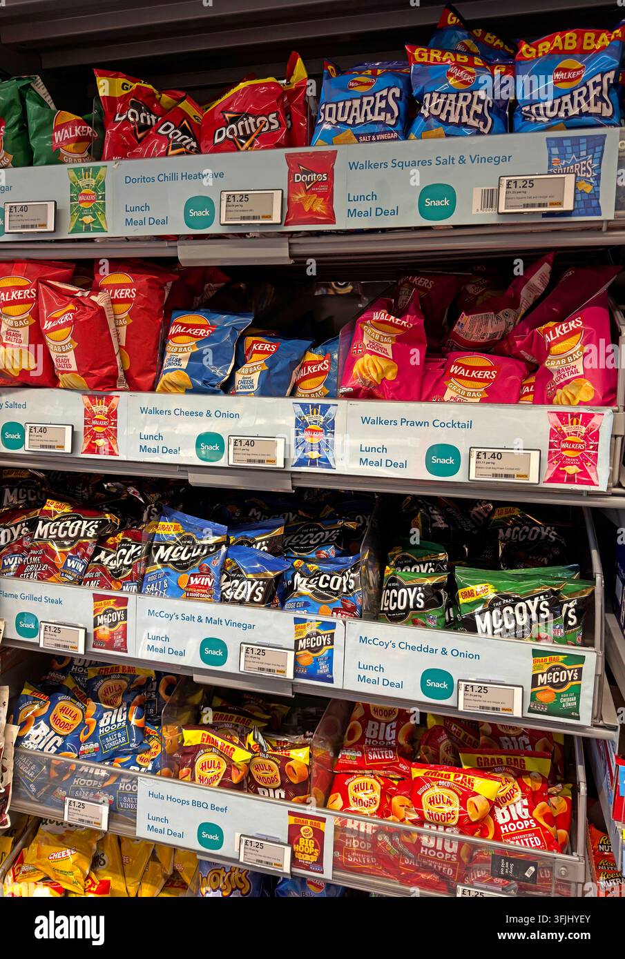 Supermarket snack aisle filled with crisps including Walkers, McCoy’s, Hula Hoops, Doritos and Squares. Stock Photo