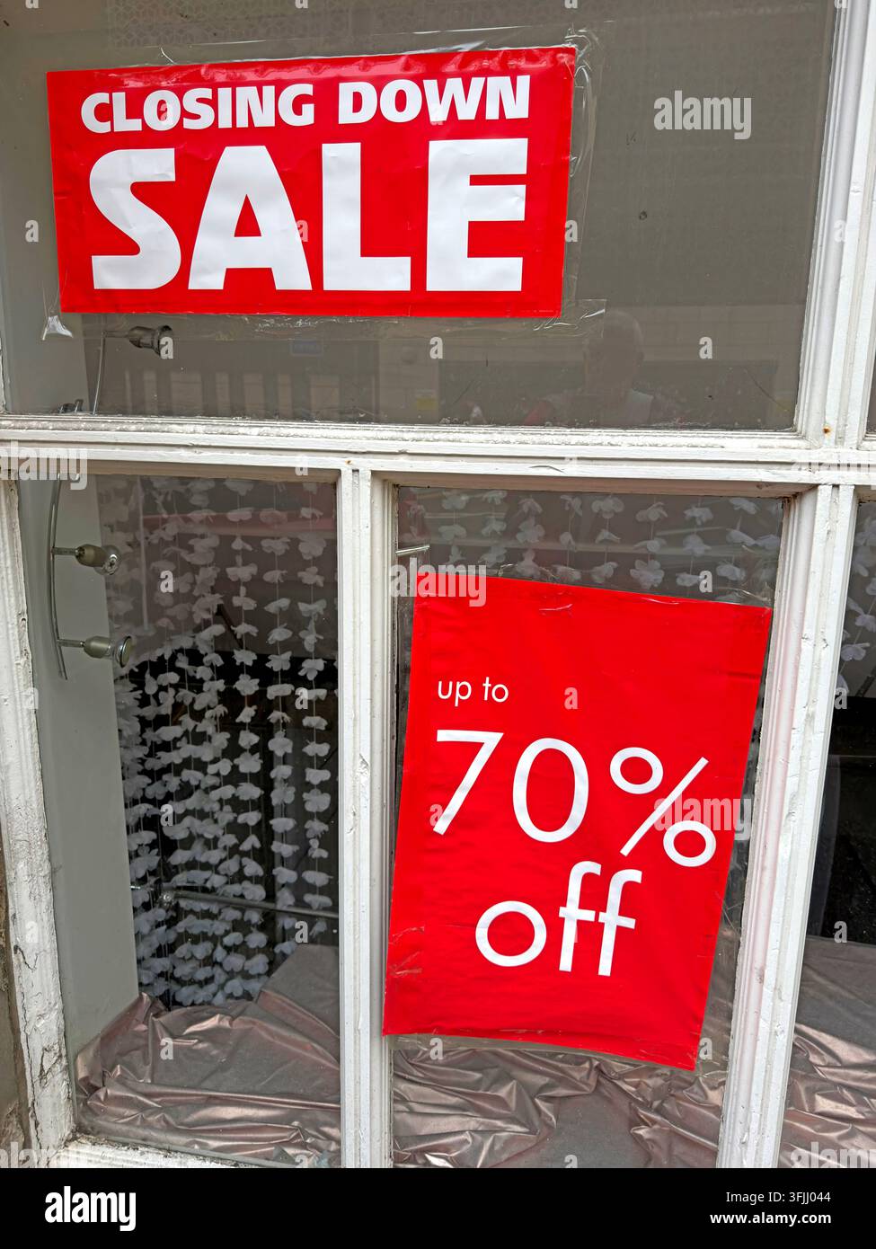 Red closing-down sale signs advertise discounts of up to 70%, illustrating pressure on shops and the changing UK high street. Stock Photo