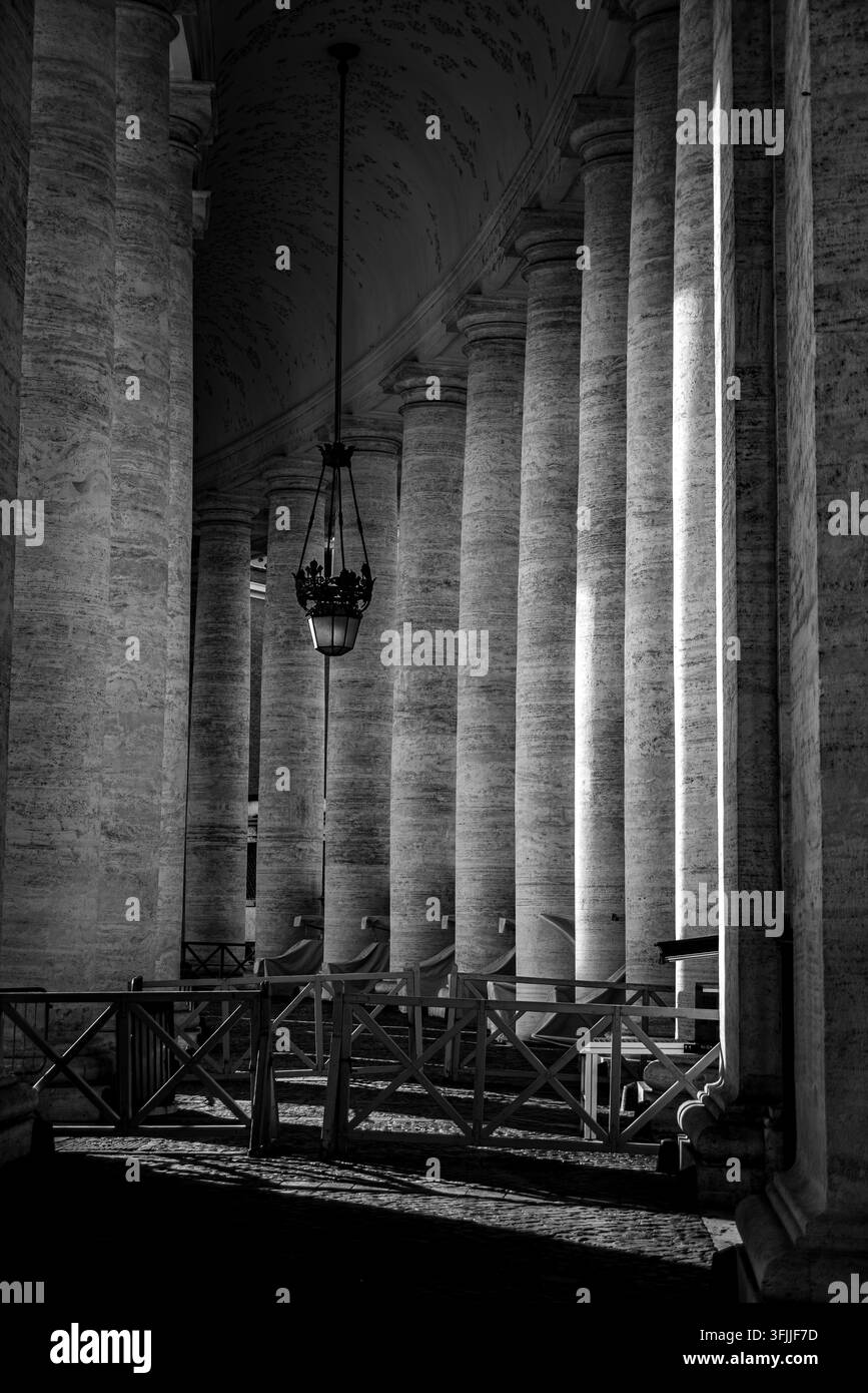 An architectural composition looking down the long covered corridor of berninis massive stone columns located in vatican city, rome, italy Stock Photo