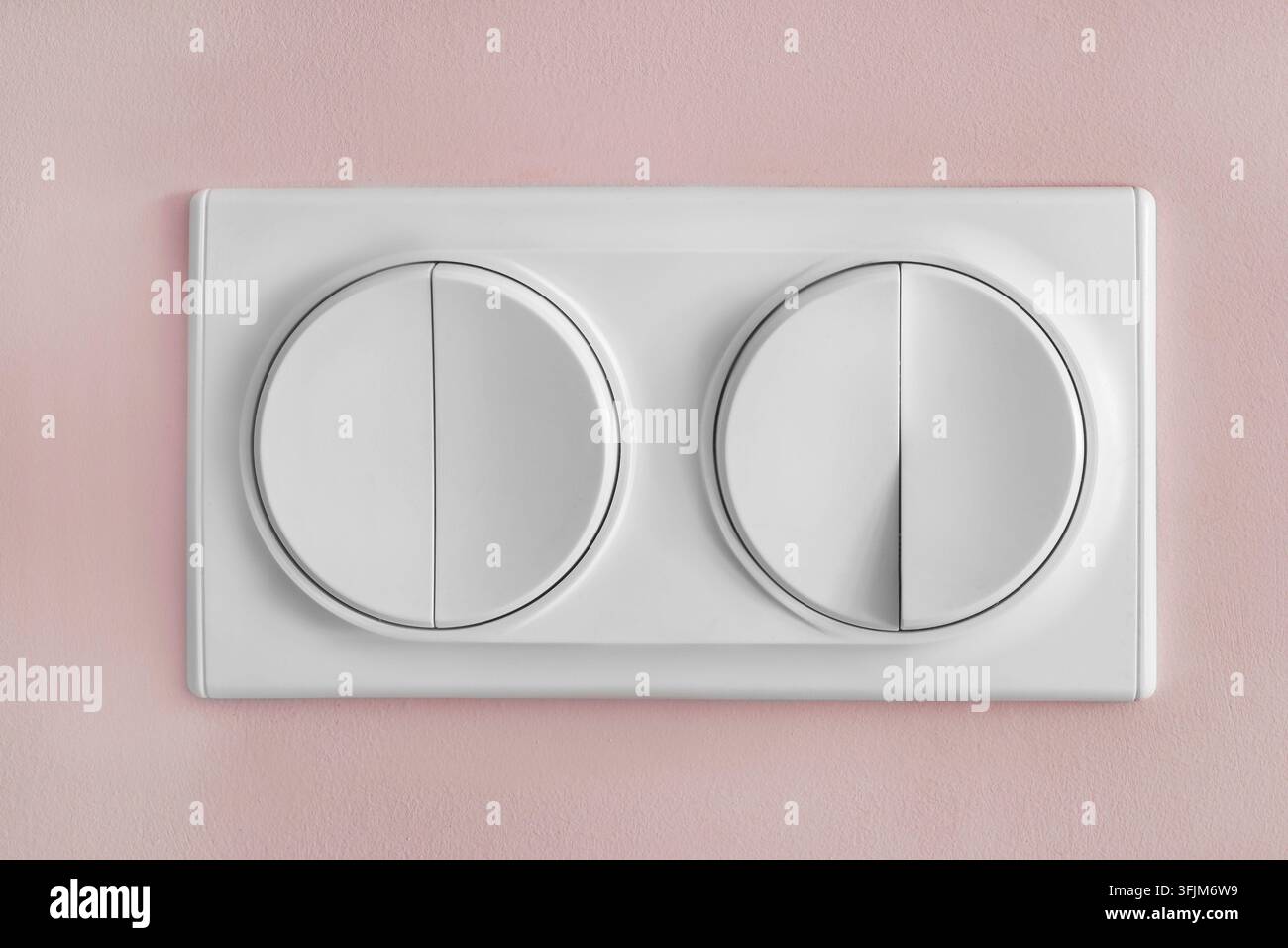 Four buttons light switch on pink painted wall closeup Stock Photo