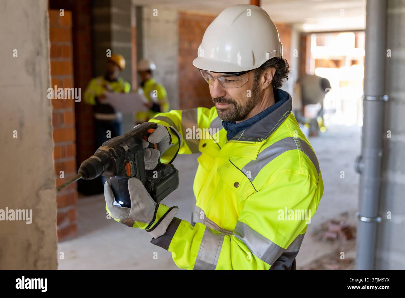 Focused builder using hammer drill on wall Stock Photo