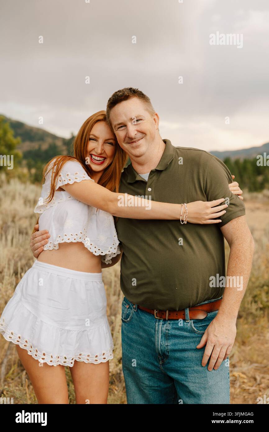 Happy young woman laughing and hugging her father outdoors Stock Photo