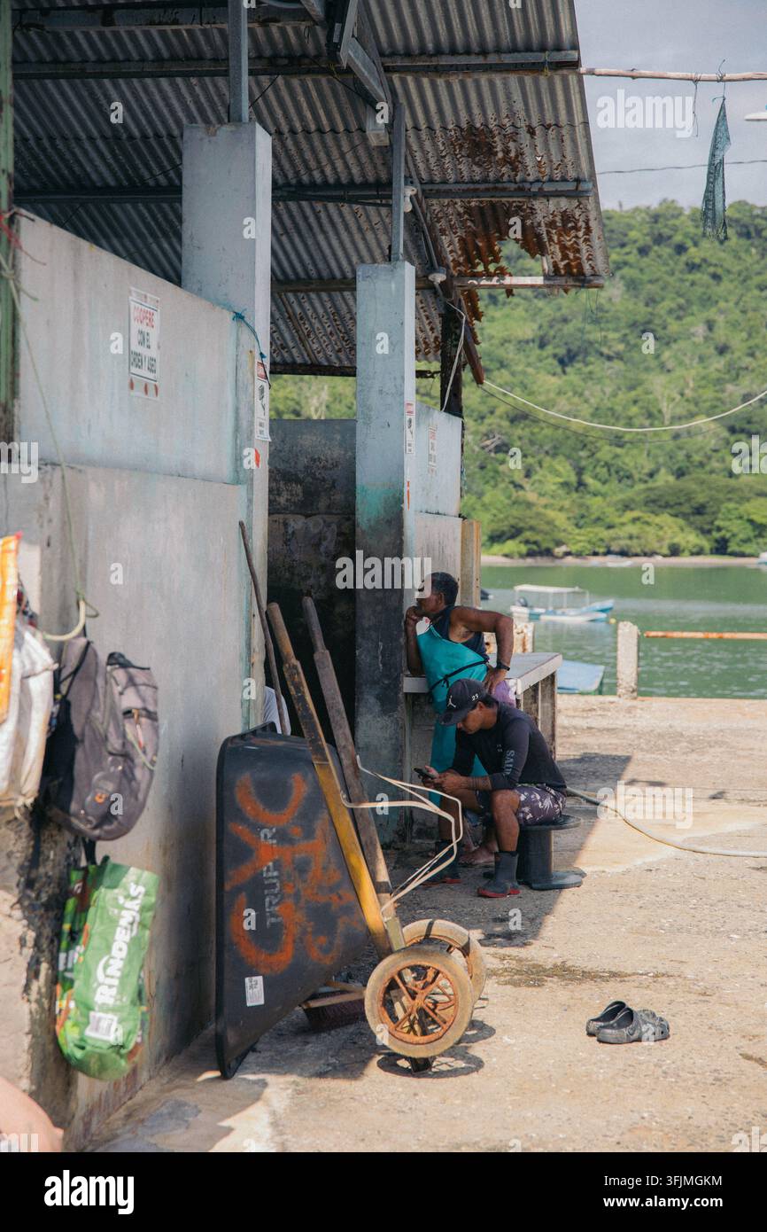 Two men taking a break at a rustic dockside Stock Photo