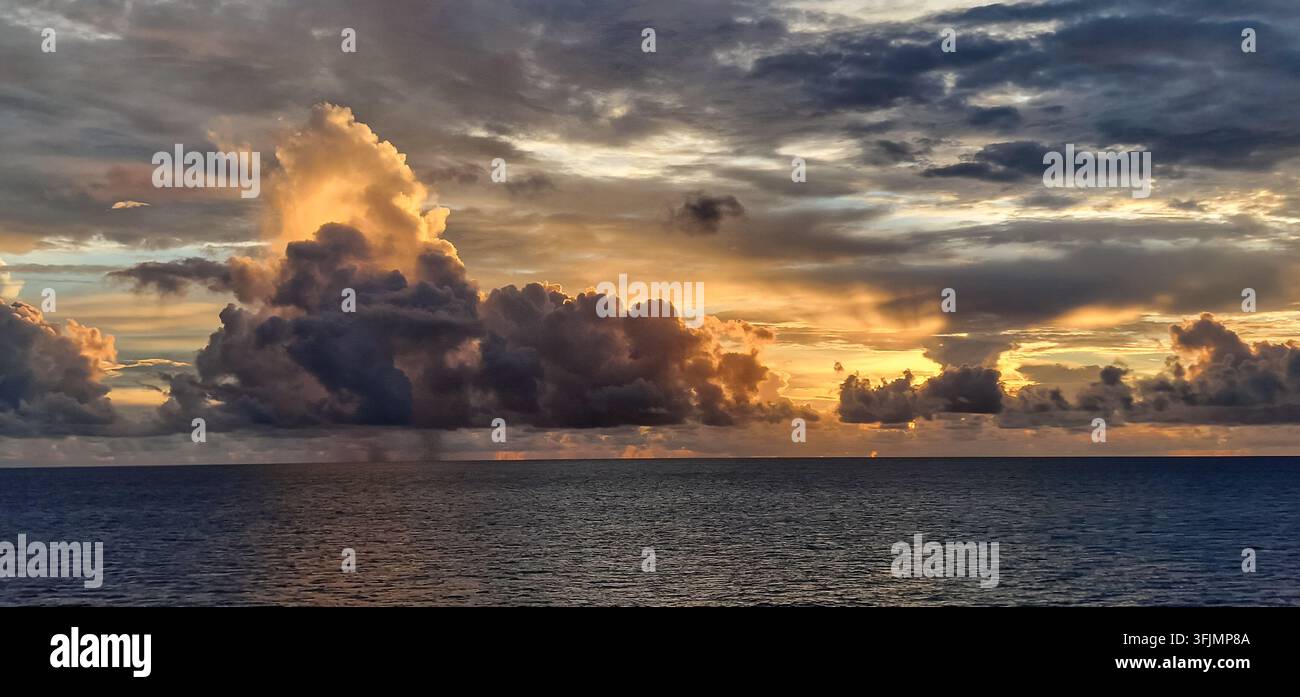 Dramatic towering clouds illuminated by warm evening sunlight over the open ocean. Stock Photo