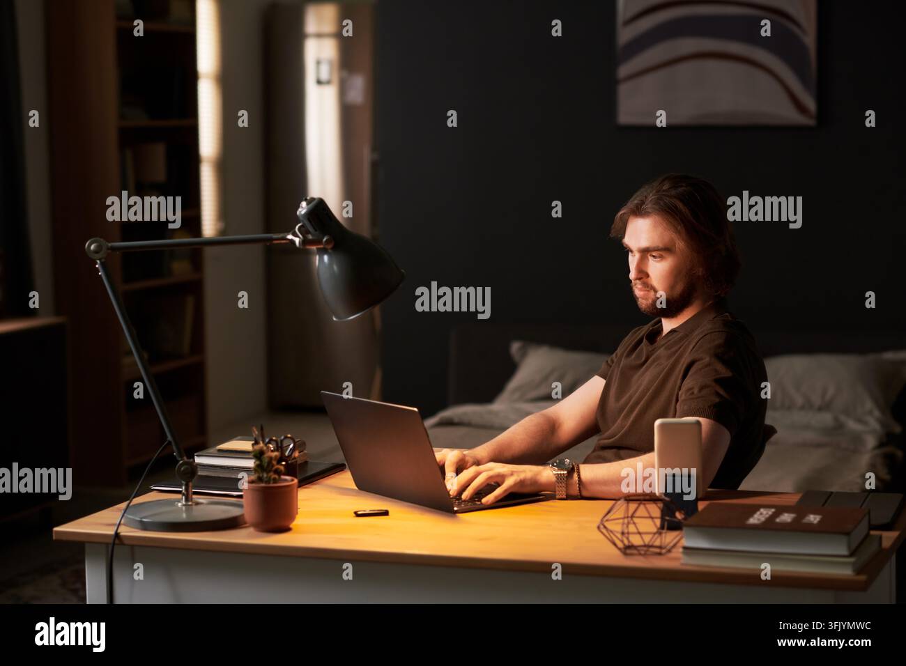 Man Typing on Laptop during Remote Work Late at Night Stock Photo