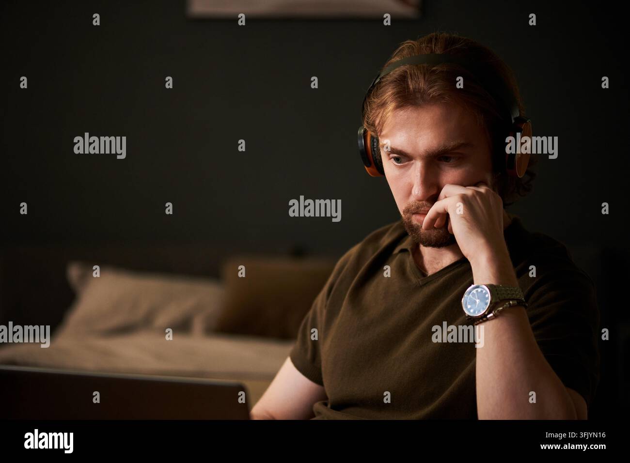 Focused Man in Headphones Working on Laptop at Home in Evening Stock Photo