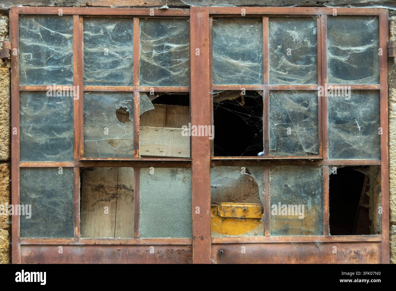 Broken glass panes covered in thick spider webs Stock Photo