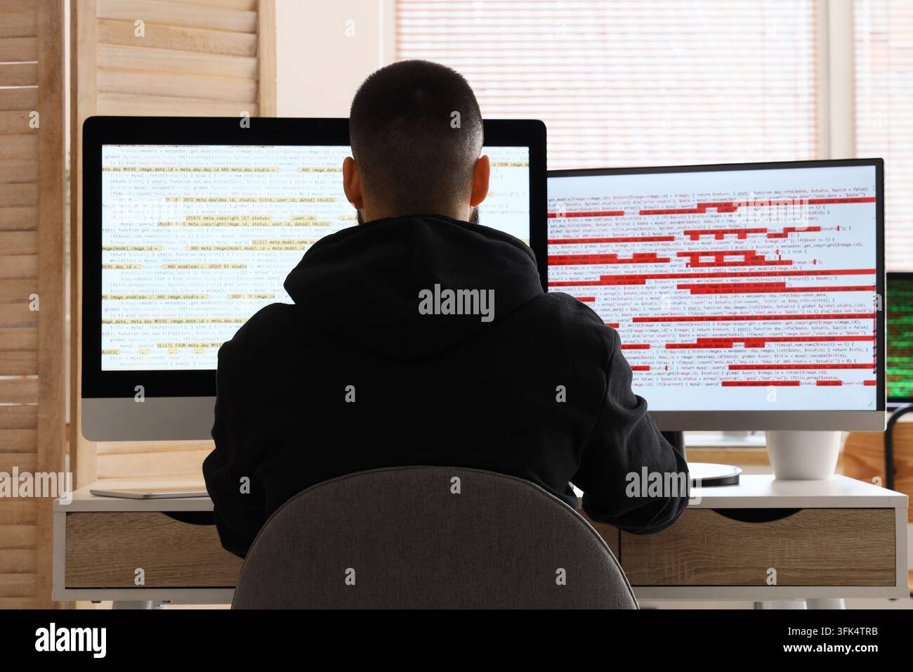 Software development and debugging, programmer working on computer code with error logs and syntax issues on dual monitors in a home office workspace Stock Photo