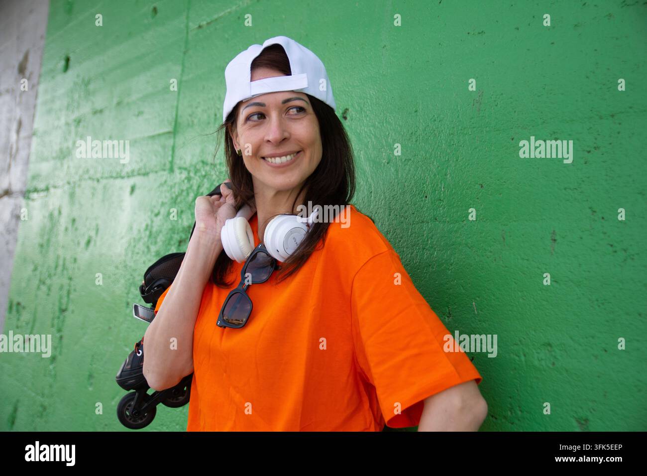 Smiling woman holding inline skates looking away outdoors Stock Photo