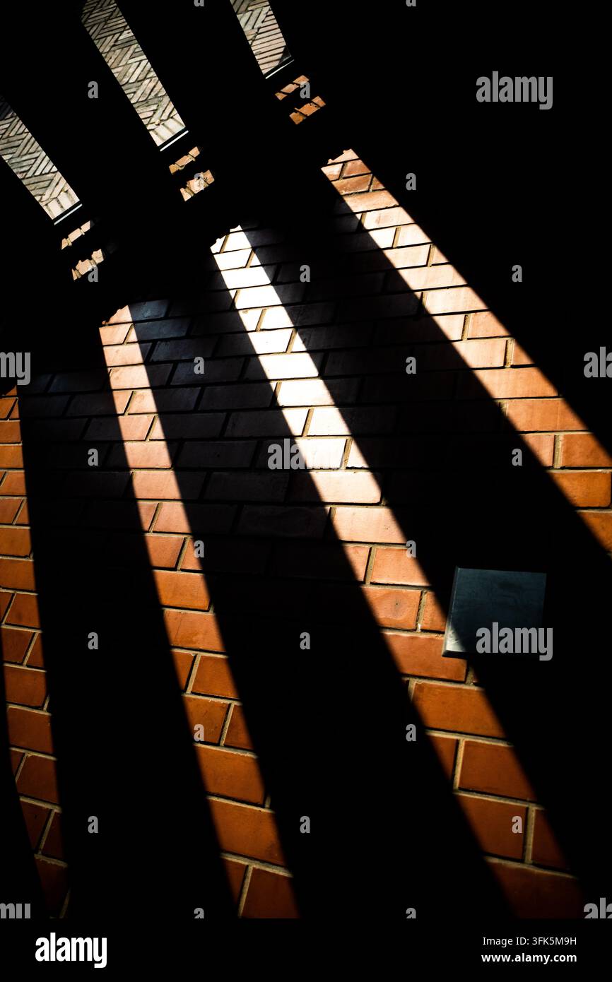 Diagonal shadow stripes from window panes on red brick wall Stock Photo