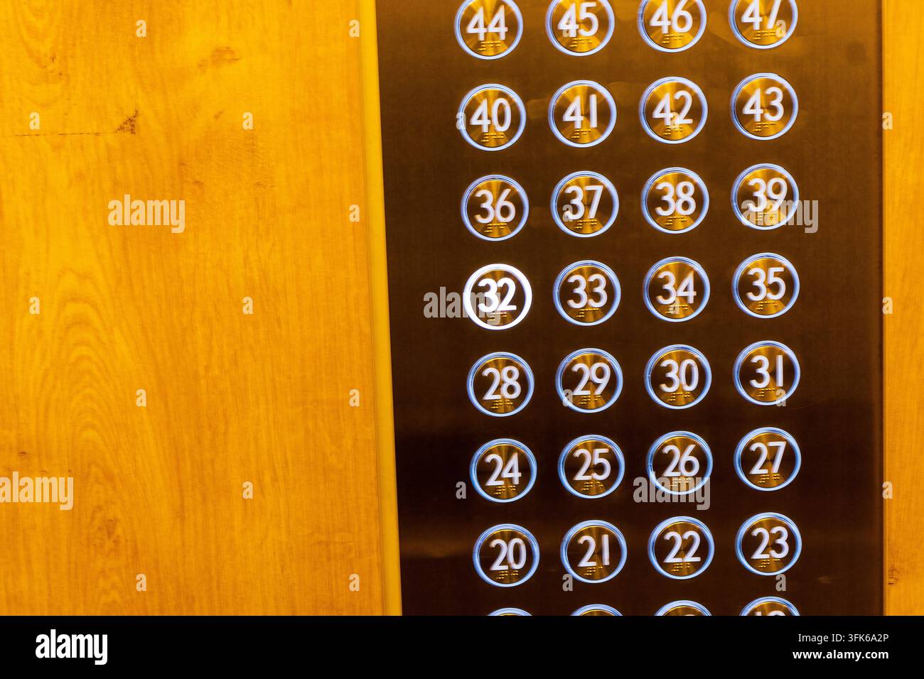 Close-up view of a modern stainless steel elevator control panel with glowing blue numbered buttons. Stock Photo