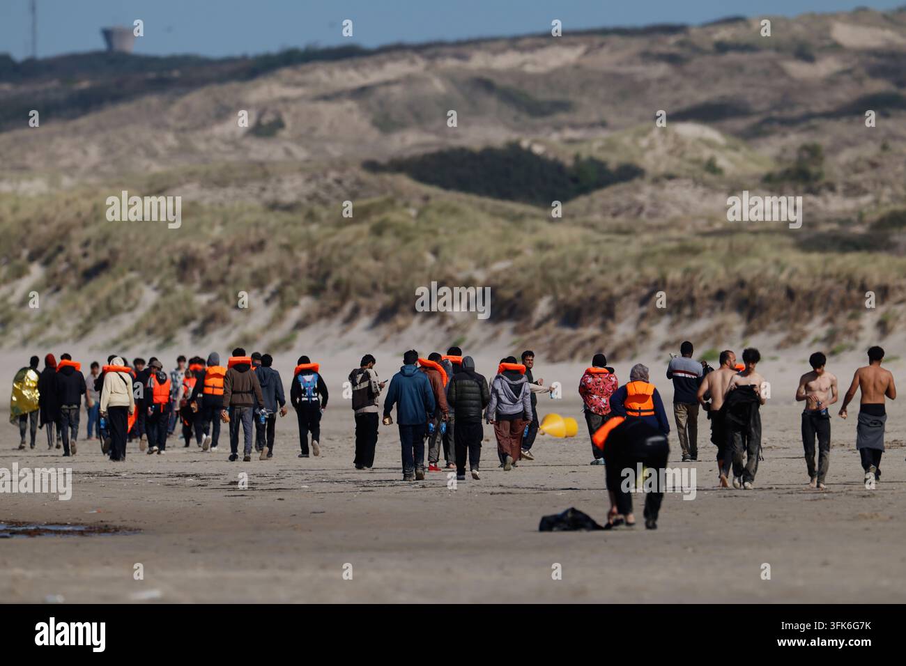 A group of migrants walk on a beach as they try to cross the channel ...