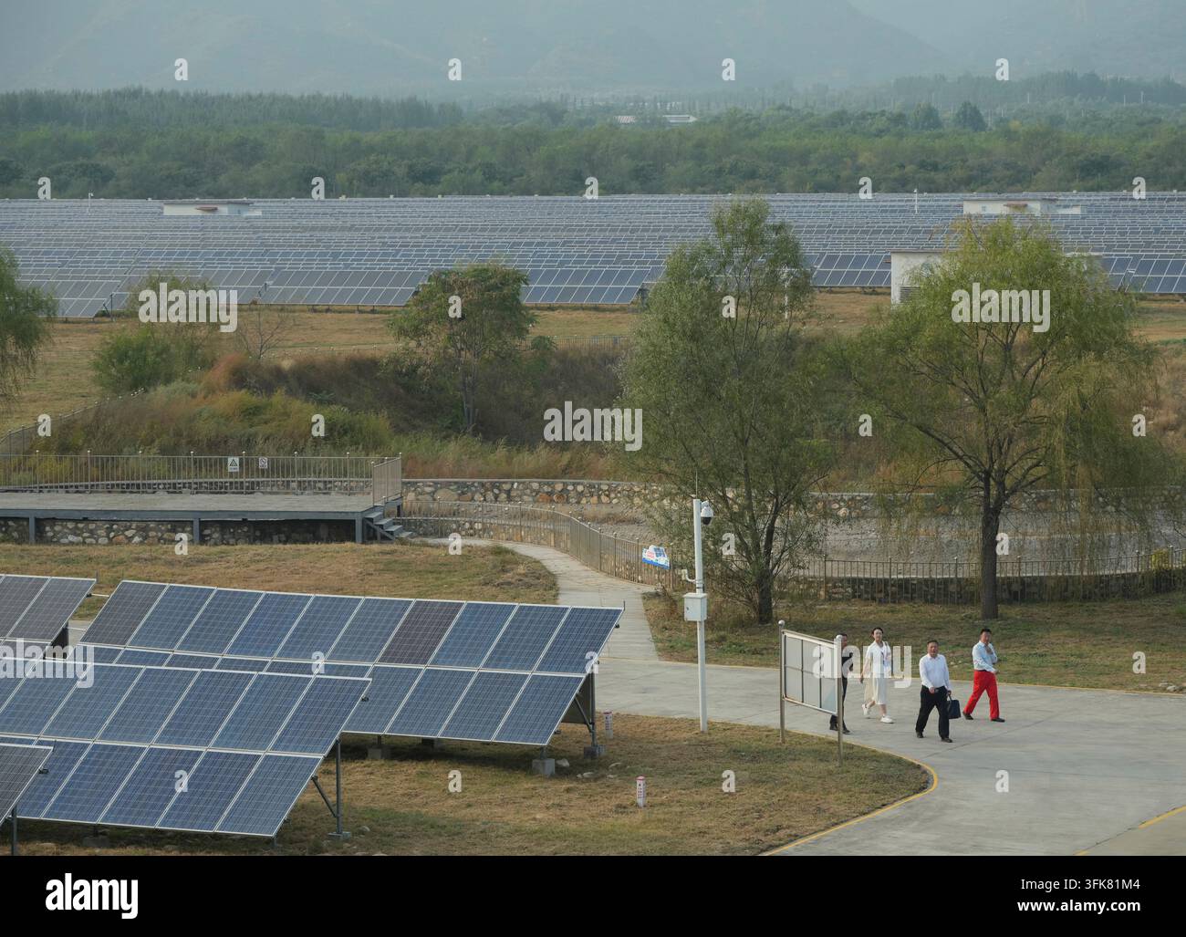 Peoples walk near solar panels at the photovoltaic station Huadian ...
