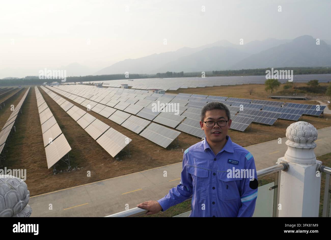 A worker stands near solar panels at the photovoltaic station Huadian ...