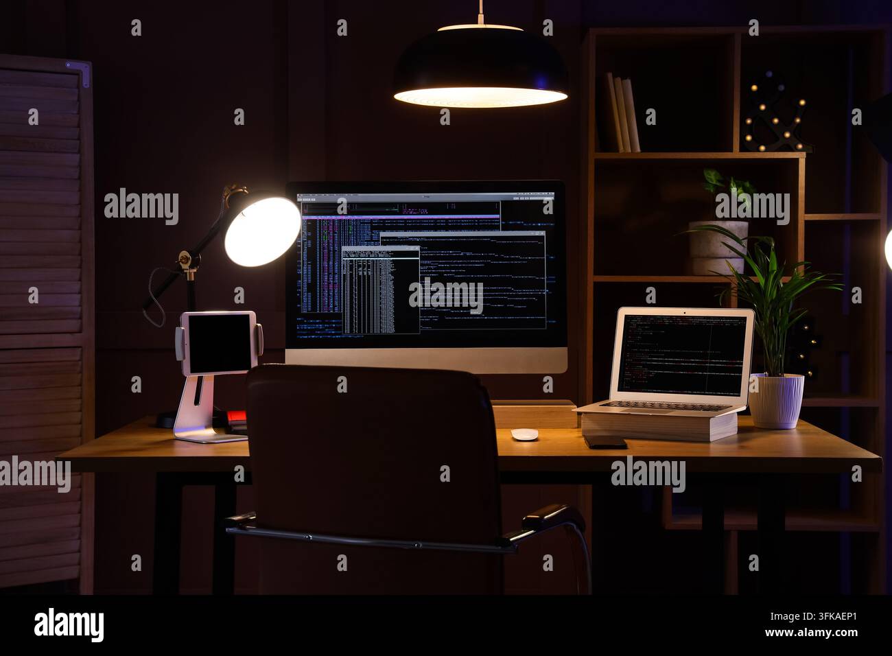 Software development and coding, programmer workspace with computer and laptop at night in home office with deadline pressure and remote work Stock Photo