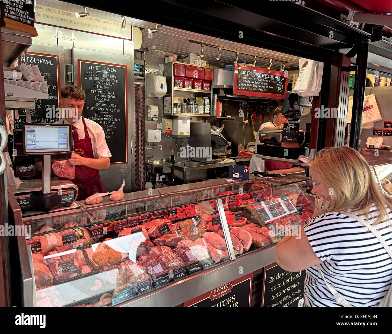 Customer buying fresh meat from a traditional butcher’s counter in York, illustrating independent food retail, skilled service and local red shopping. Stock Photo