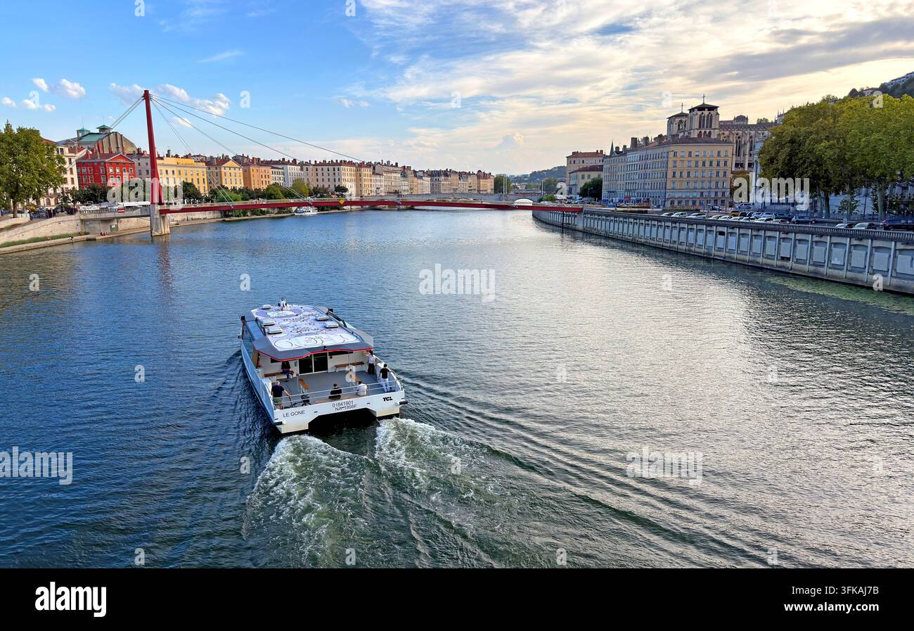 TCL Navigône public transport river shuttle on the Saône in central Lyon, with historic quays and the red Palais de Justice footbridge nearby. Stock Photo