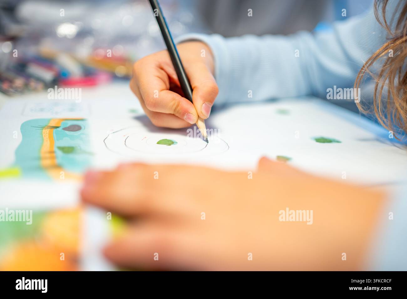 First grade student practices writing letters with pencil in workbook. Early literacy and handwriting skills develop with selective focus and shallow Stock Photo