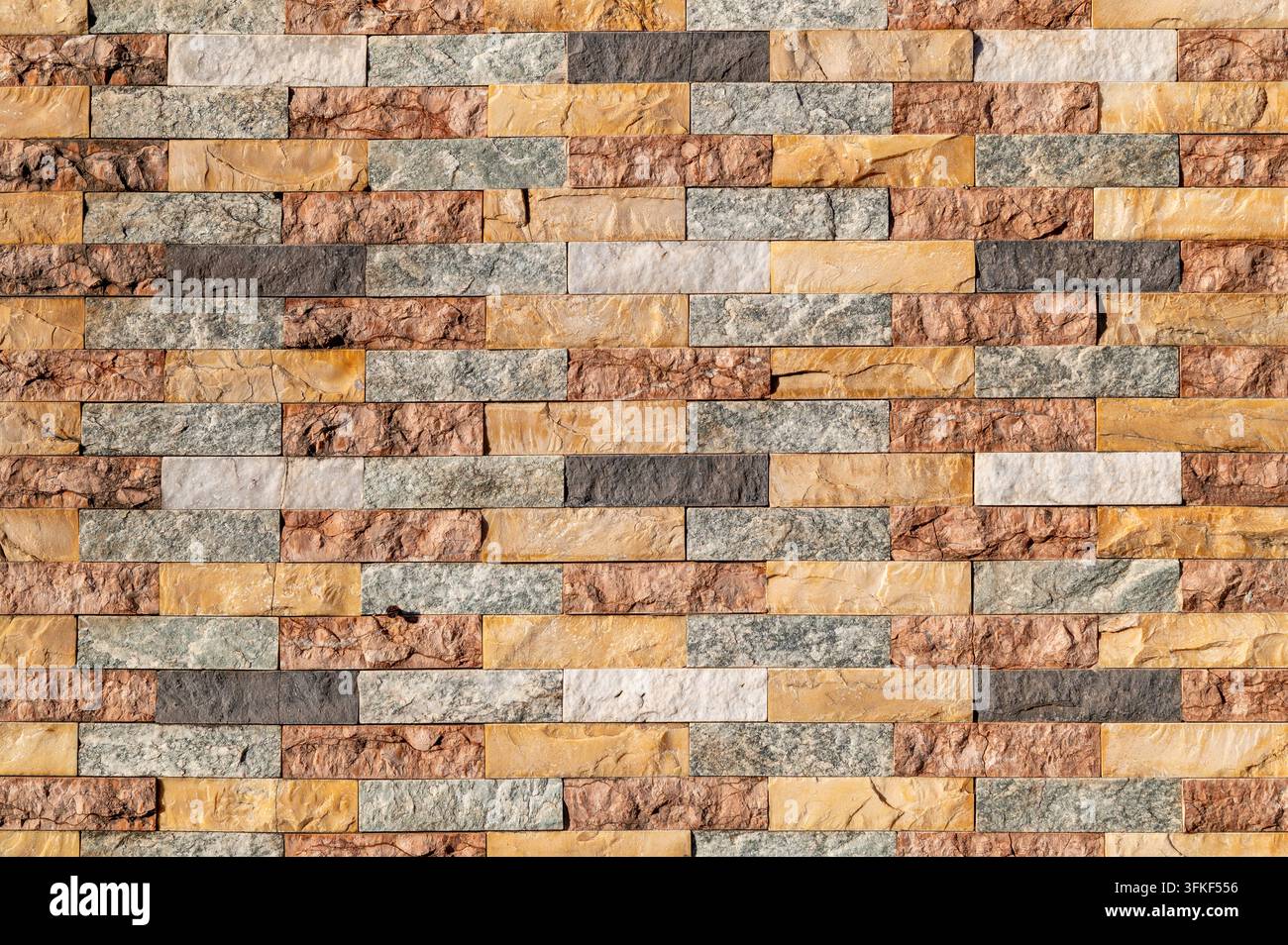 Multicolored stacked stone tiles arranged in horizontal pattern on wall. Stock Photo