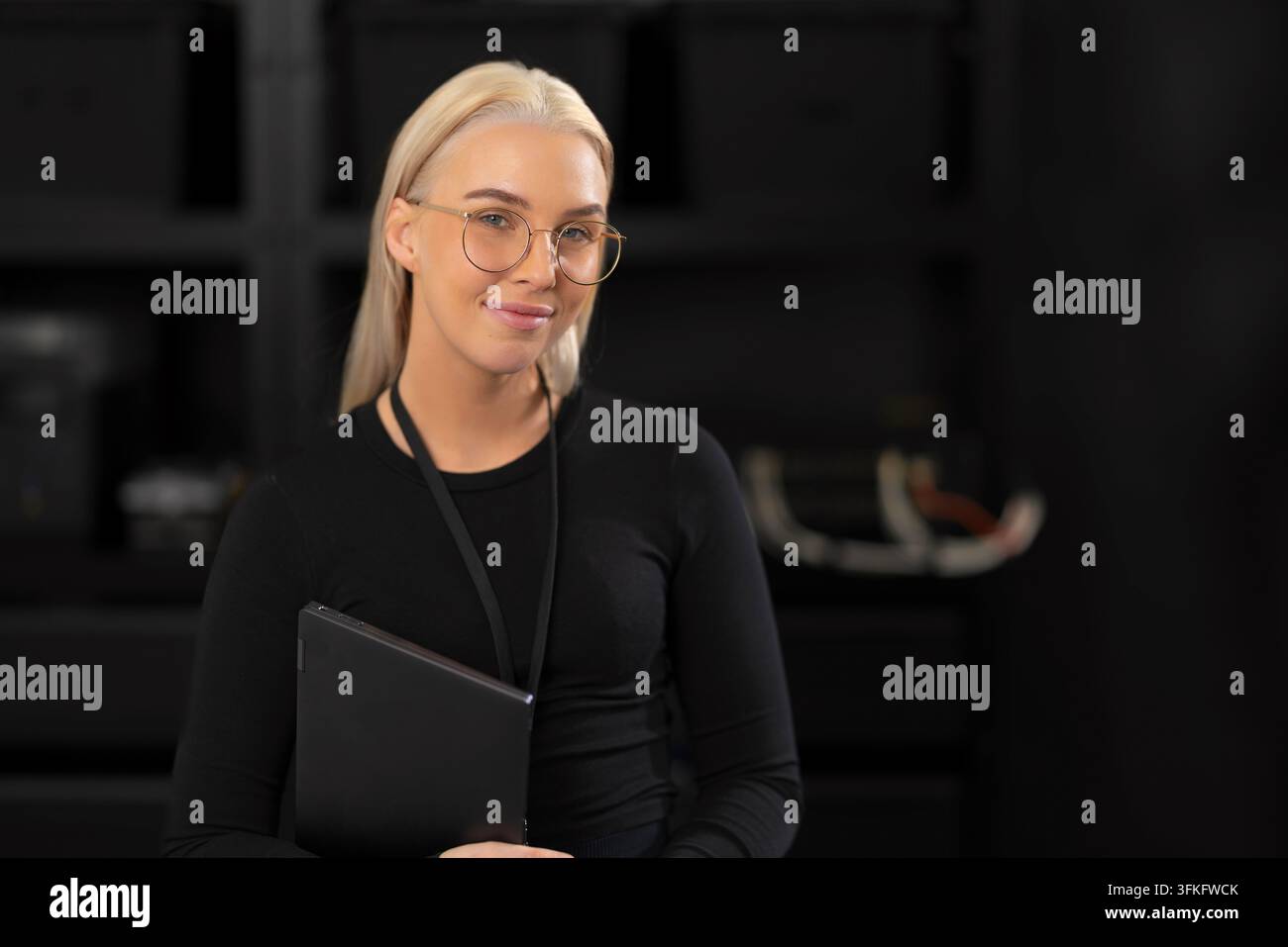 Professional female IT consultant with tablet in a dark studio, ready for tech and cybersecurity topics Stock Photo