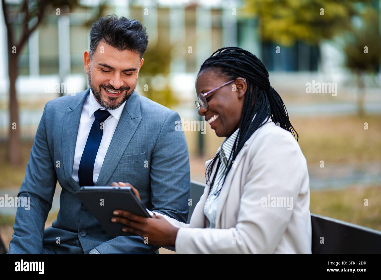 Diverse business colleagues working together outdoors using tablet Stock Photo
