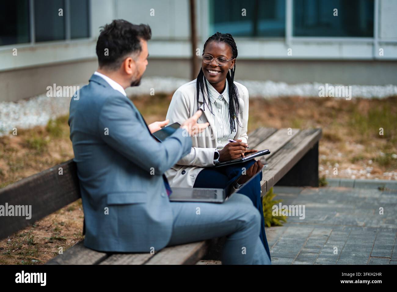 Business colleagues collaborating outdoors on digital devices Stock Photo