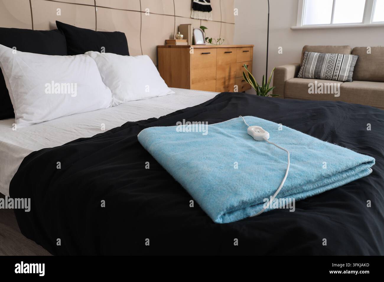 Blue electric heating pad on bed in room Stock Photo