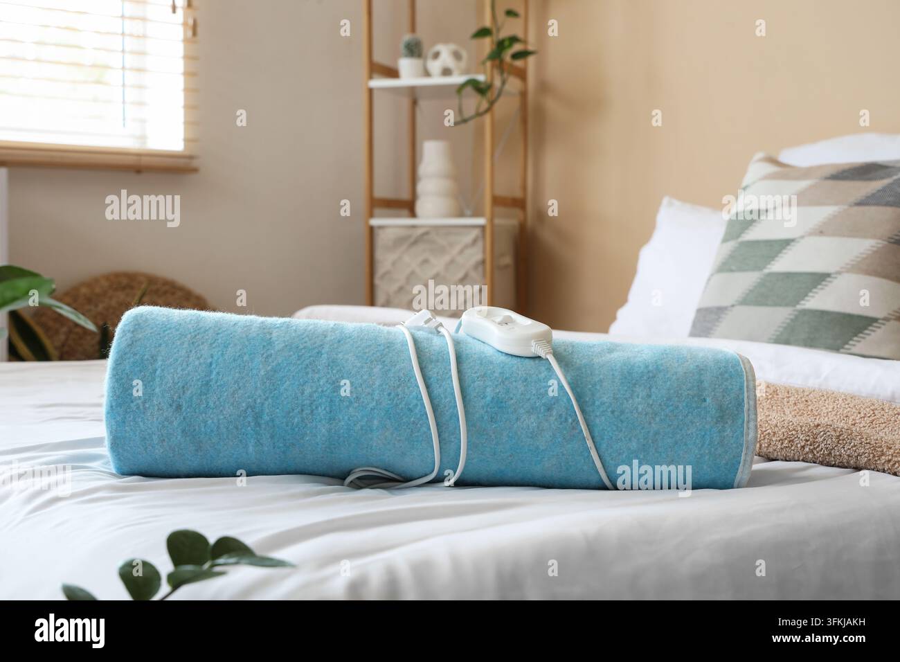 Folded electric heating pad on bed in room Stock Photo