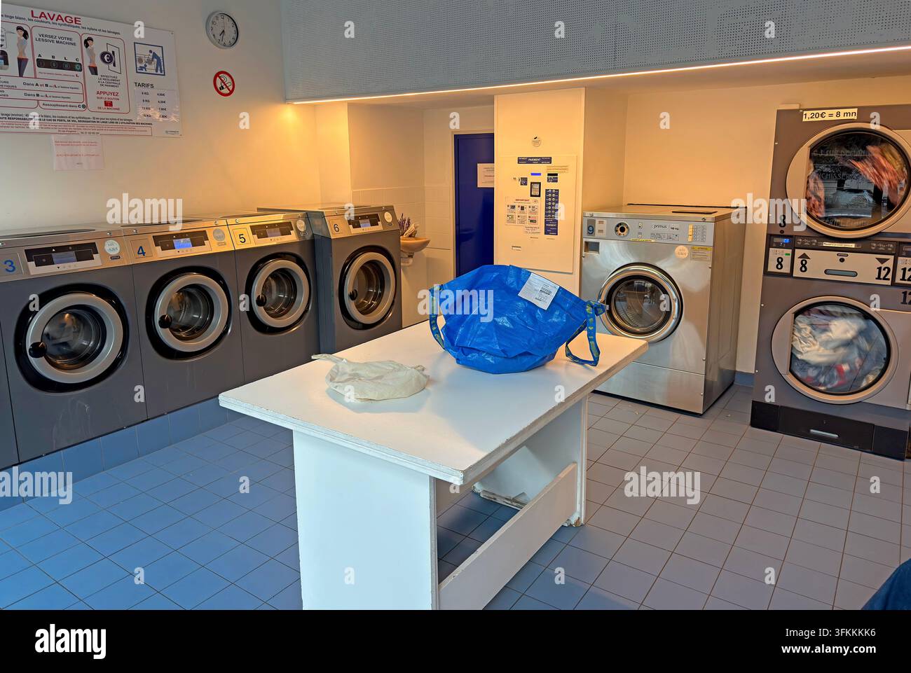 Self-service launderette interior in Lyon, France, with rows of washing machines and tumble dryers. Stock Photo