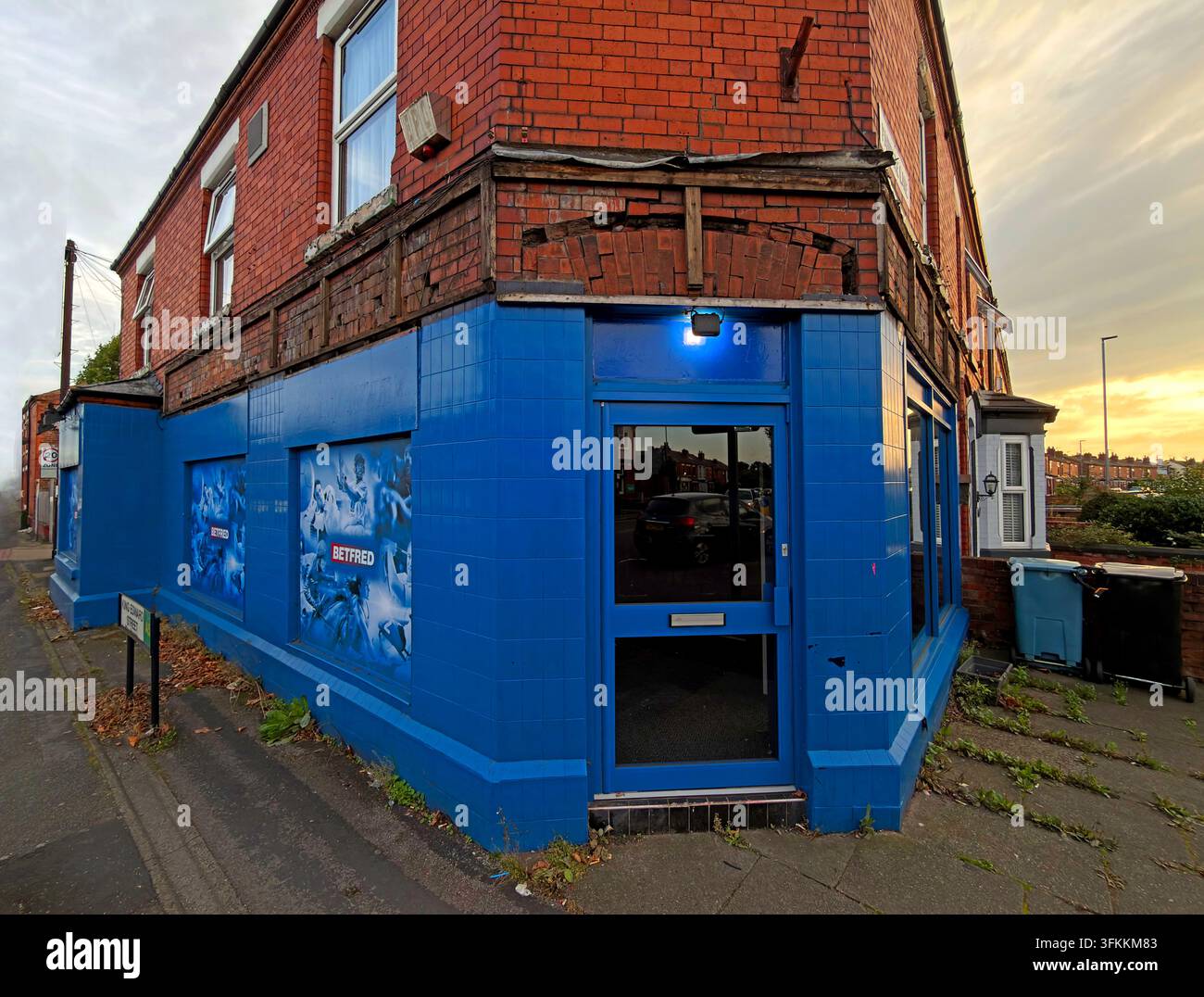 Sunset on closed & now empty Betfred betting shop at 137 Padgate Lane in Warrington, with blue shutters and former shop branding. Stock Photo