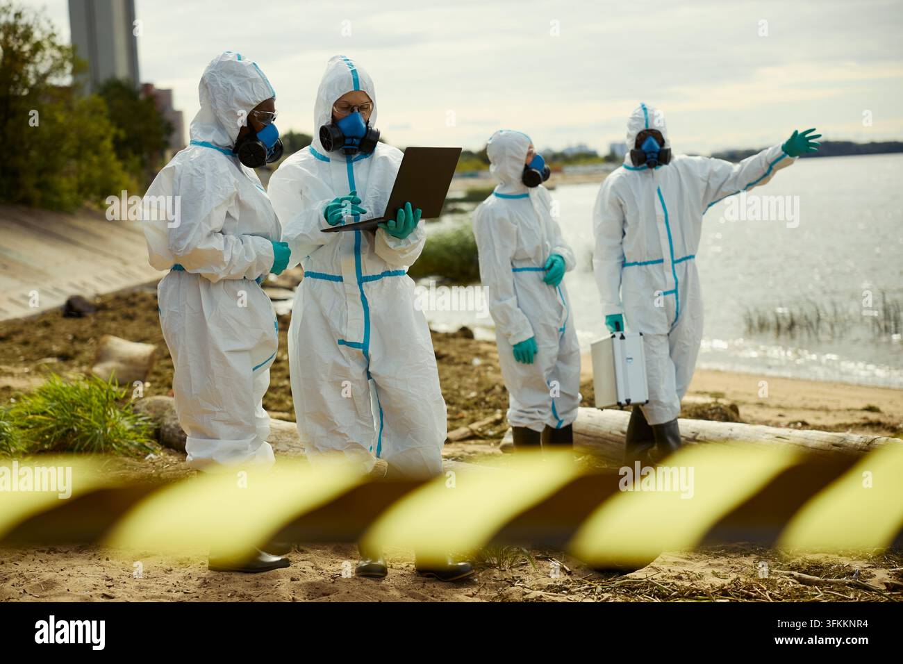 Ecologists in Hazmat Suits Analyzing Water Pollution Data Stock Photo