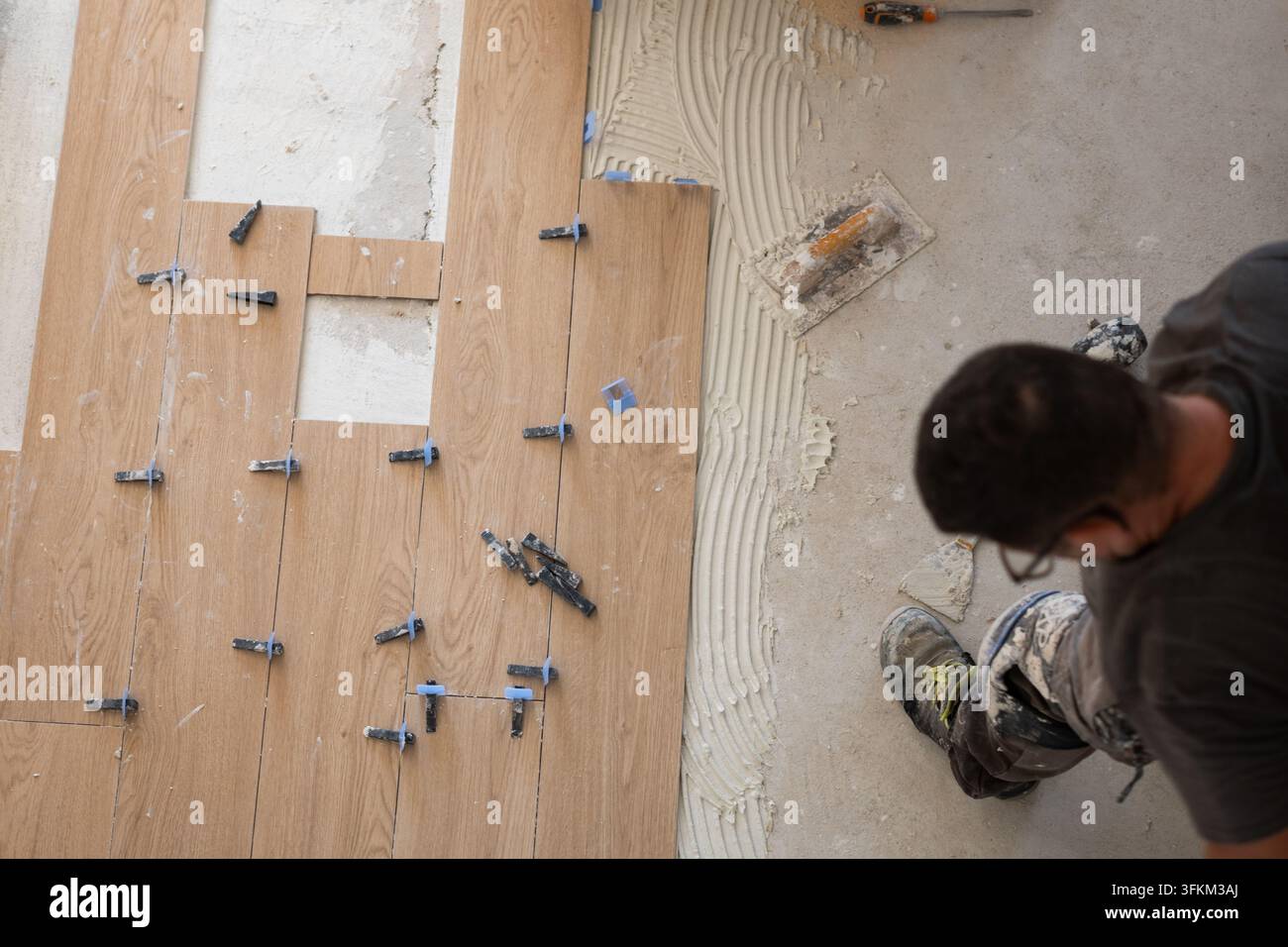 Worker laying down new ceramic tiles with adhesive and leveling system Stock Photo