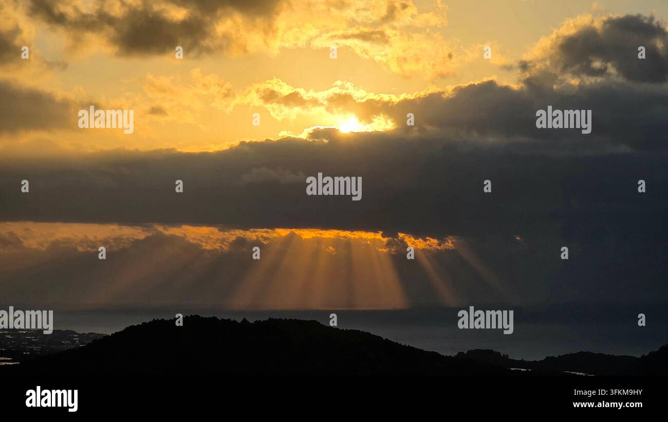 Sunbeams breaking through dramatic clouds over the sea Stock Photo