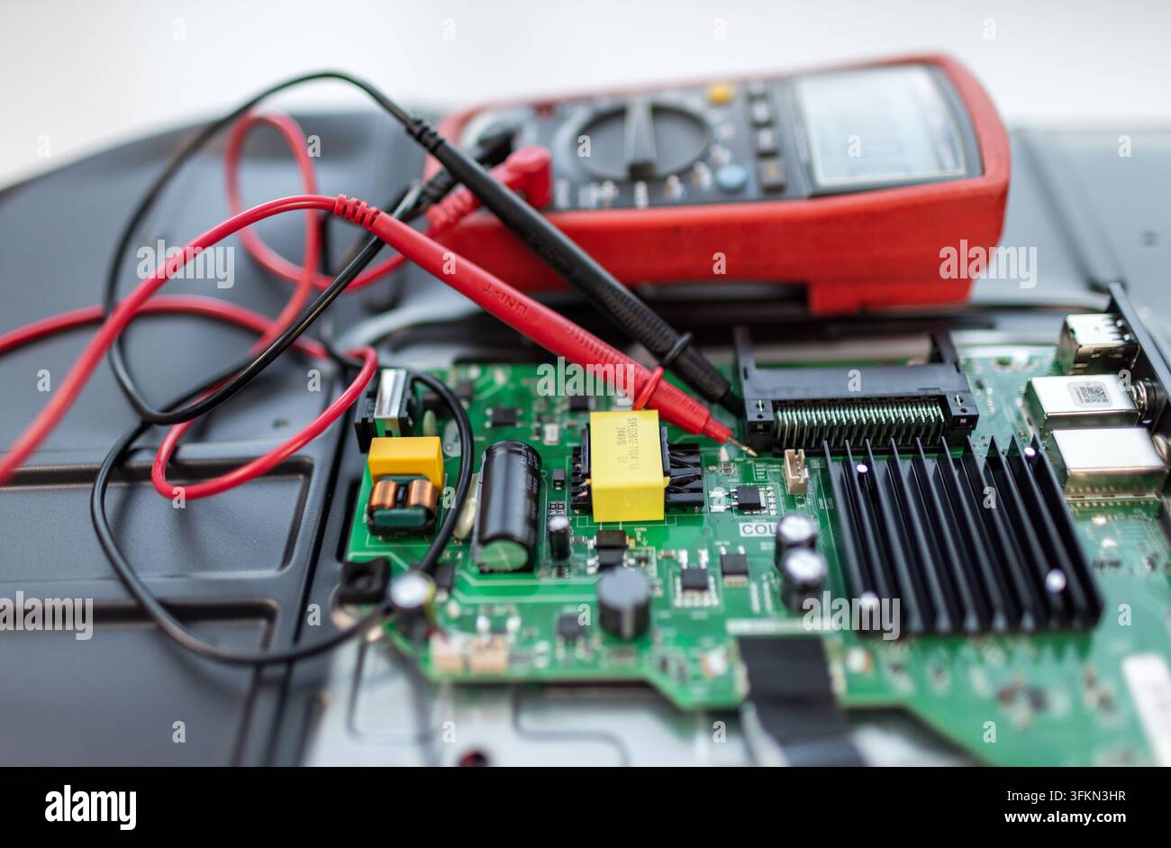 Red multimeter probes test green circuit board components Stock Photo