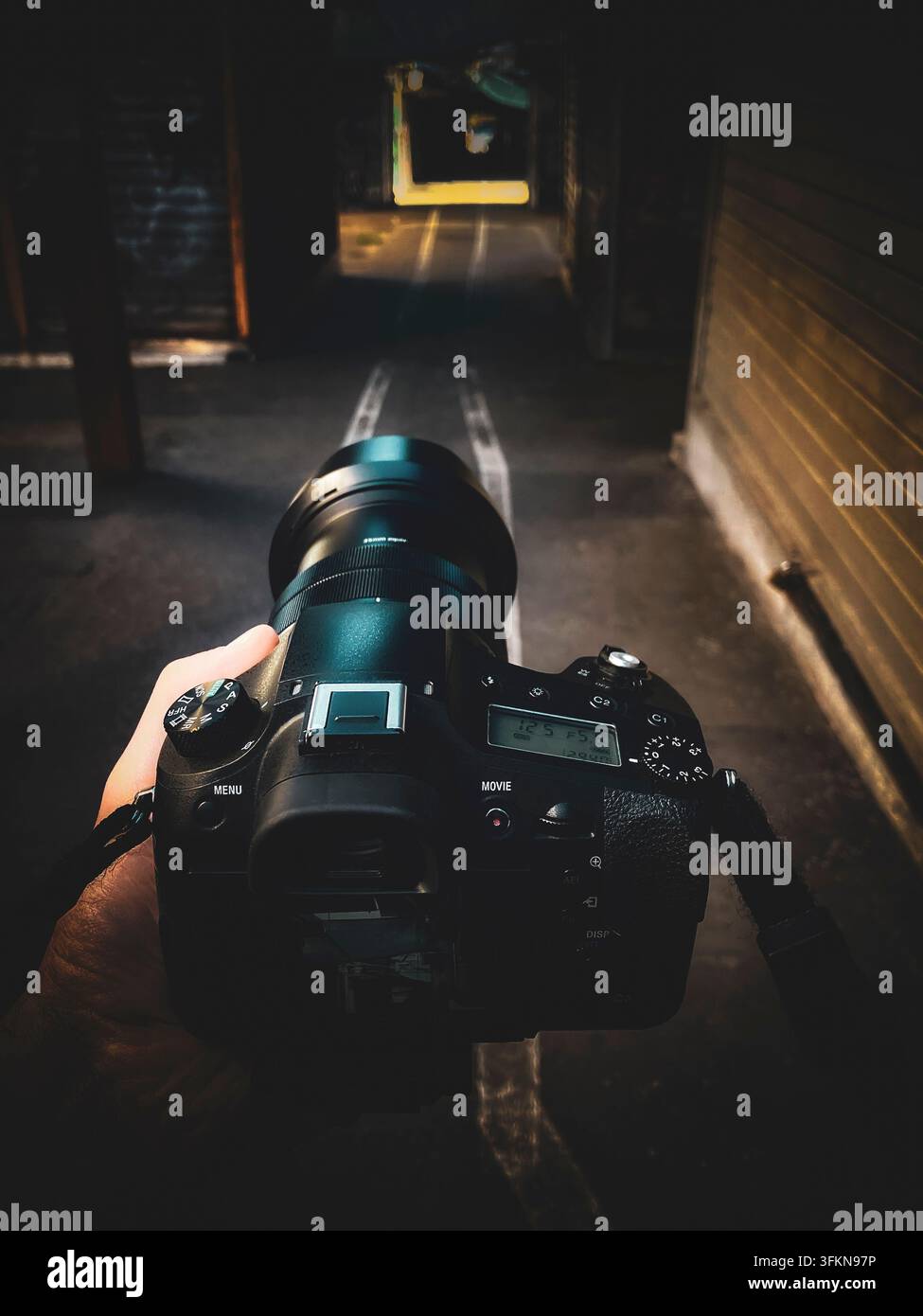 Hand holding professional camera with telephoto lens in narrow covered market passage with cinematic editing in Rome, Italy - Smartphone Captured Stock Image