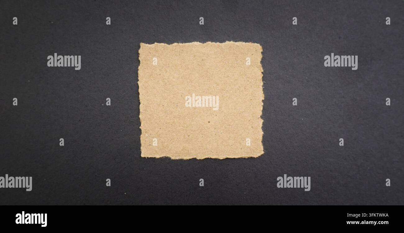 torn beige paper square centered on a dark textured background, suitable for message, note, copy space, and handmade design concepts. Stock Photo