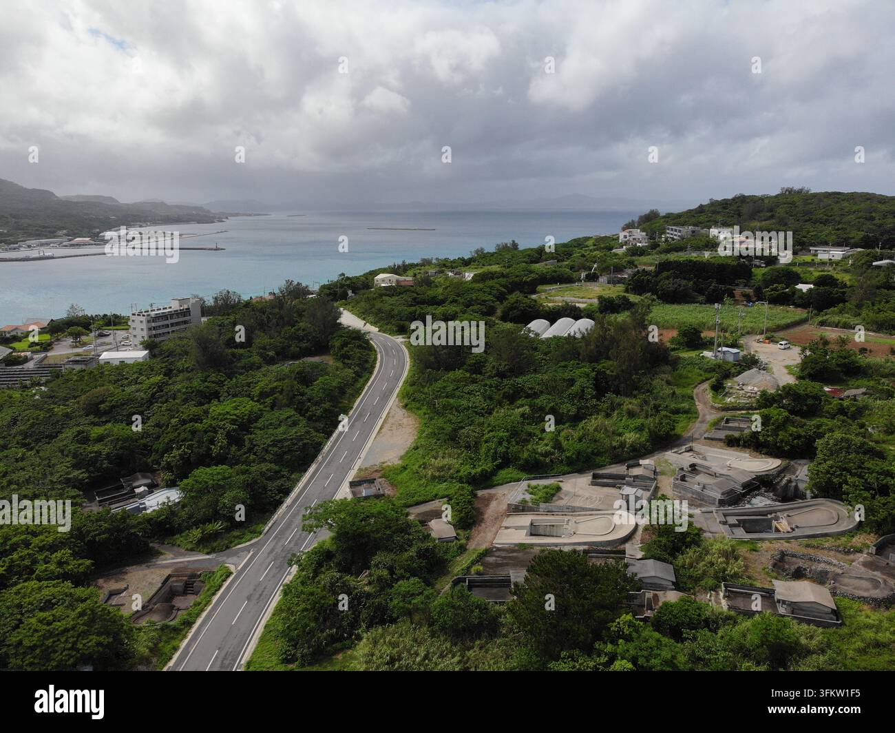 Aerial view of a winding asphalt road cutting through lush green ...