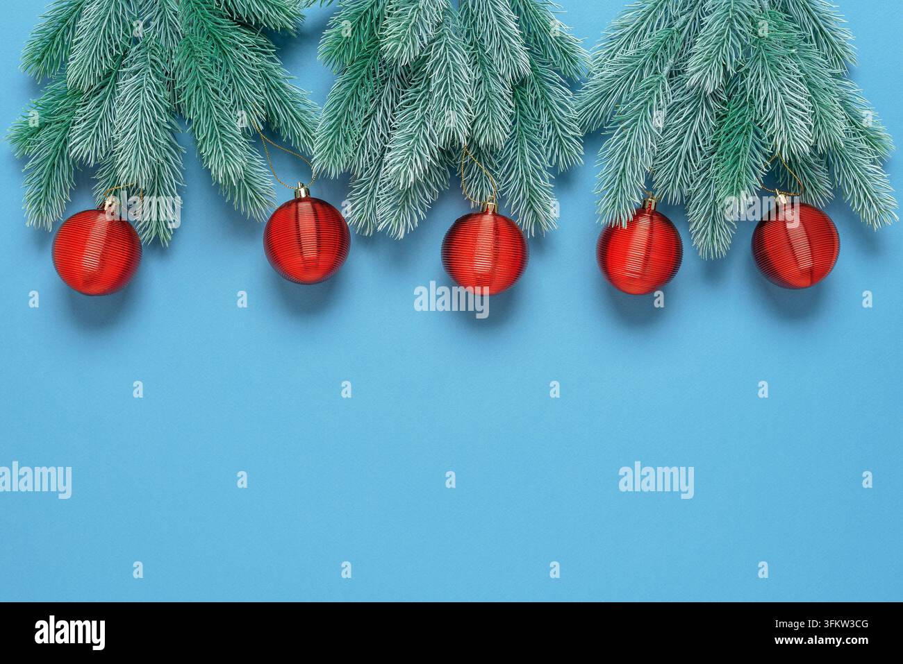 Border from decorative fir branches and red Christmas balls on a blue ...