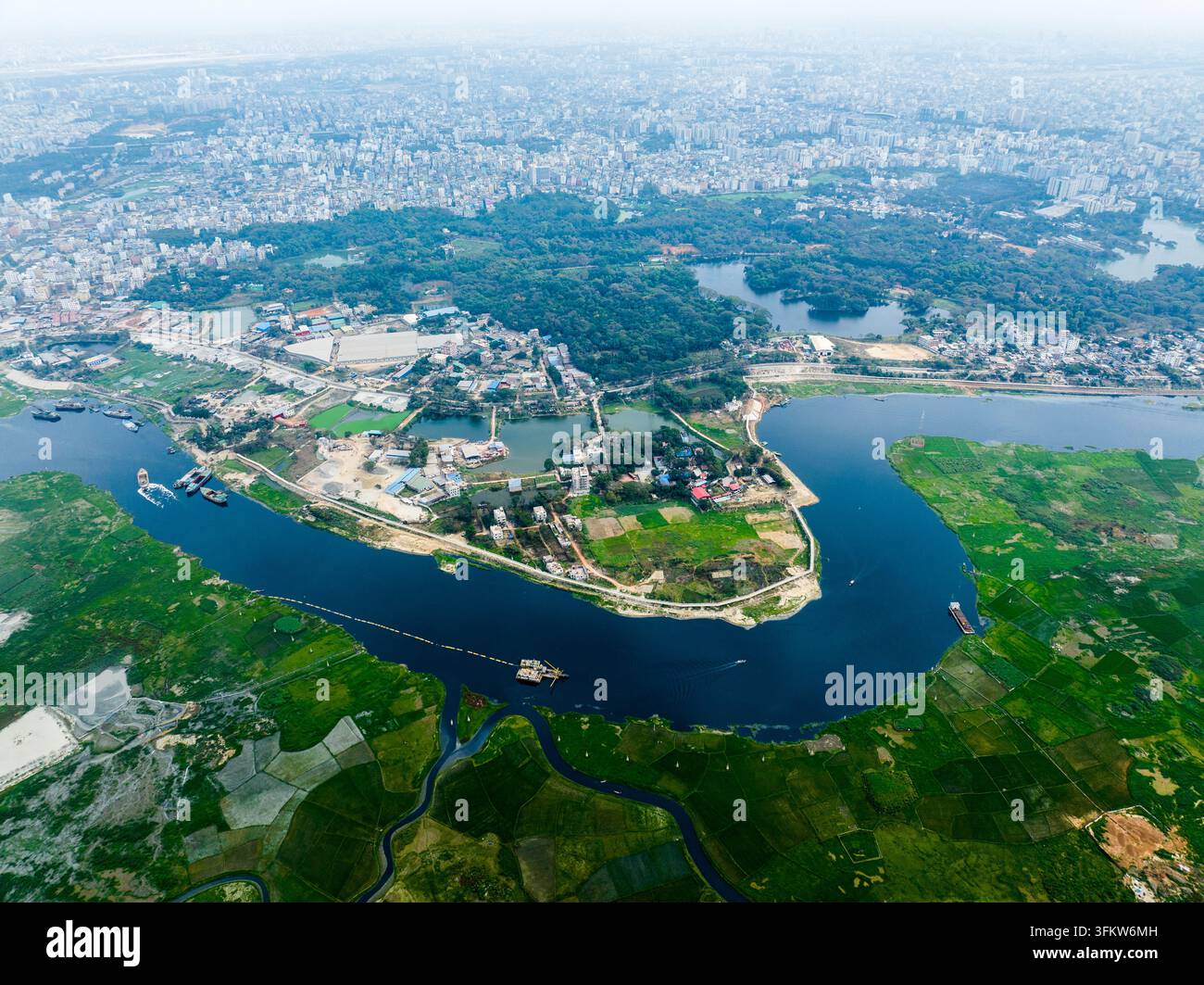 Aerial view of the winding river flowing through lush green fields and ...