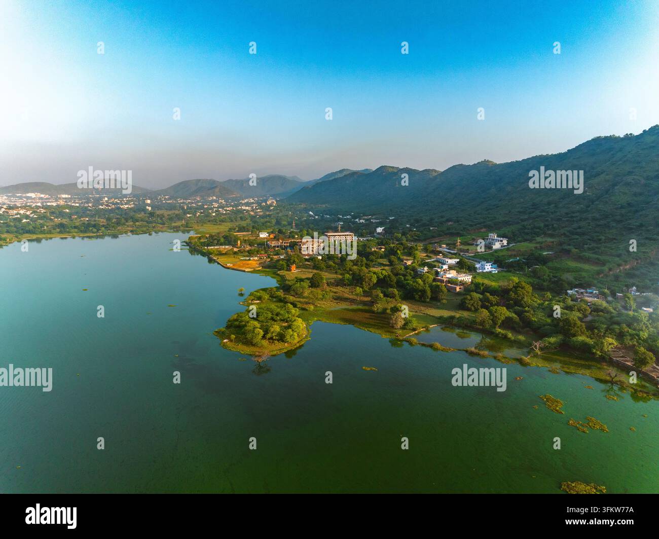 Aerial view of a serene lake surrounded by lush green hills and ...