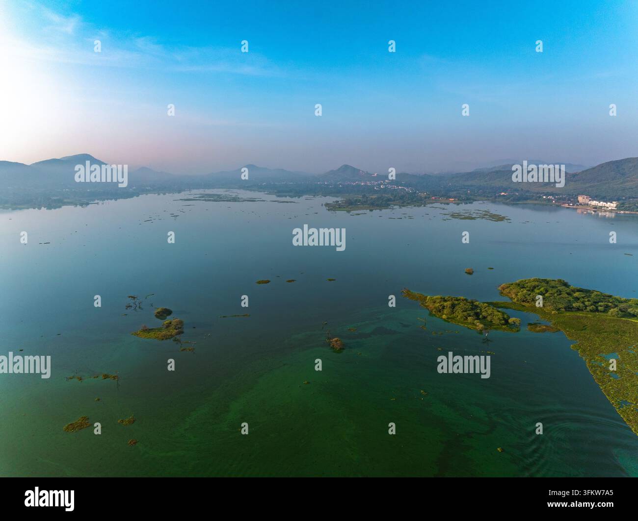 Aerial view of a serene lake with lush green islands and distant hills ...